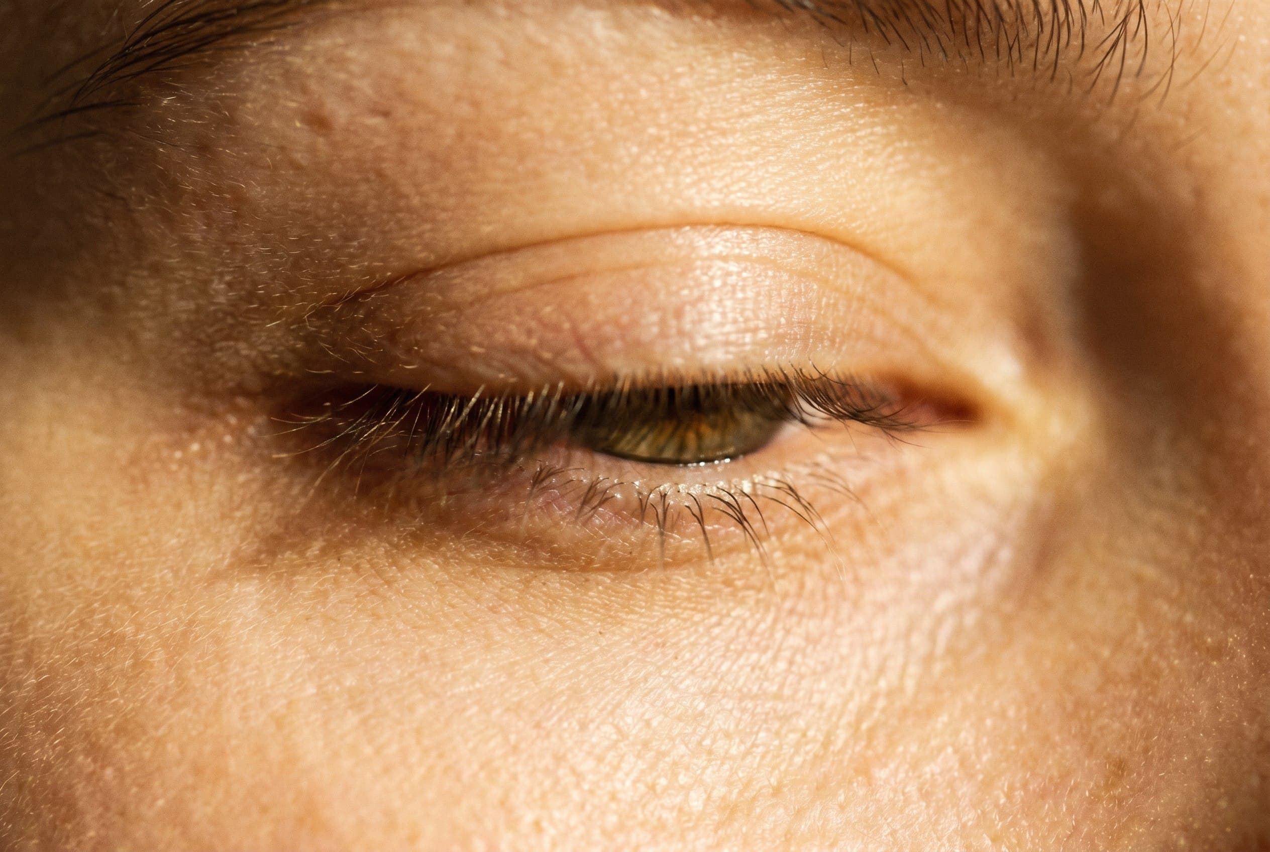 An editorial close-up of the eye area in soft warm light