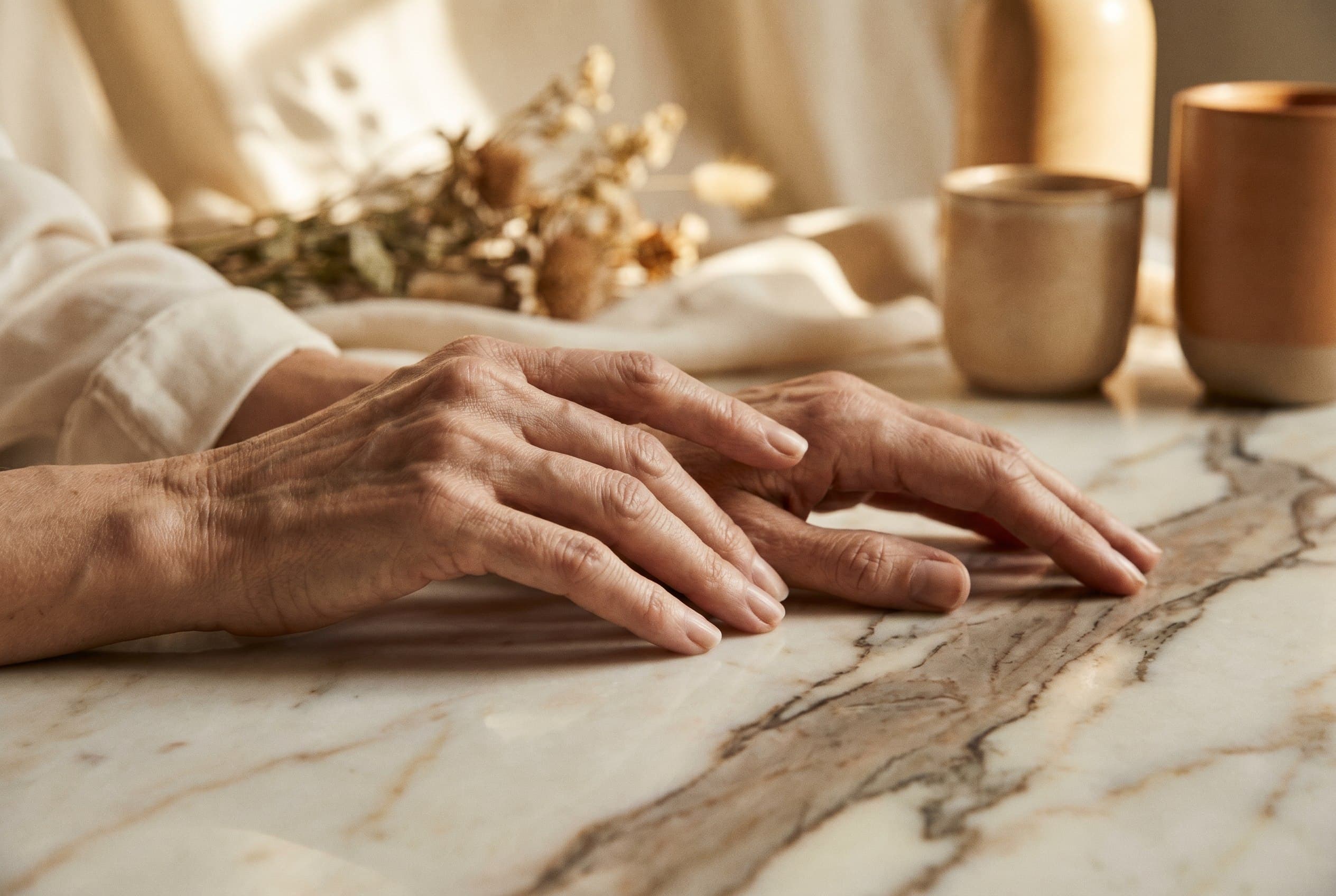 A pair of hands resting on a marble surface in warm directional light
