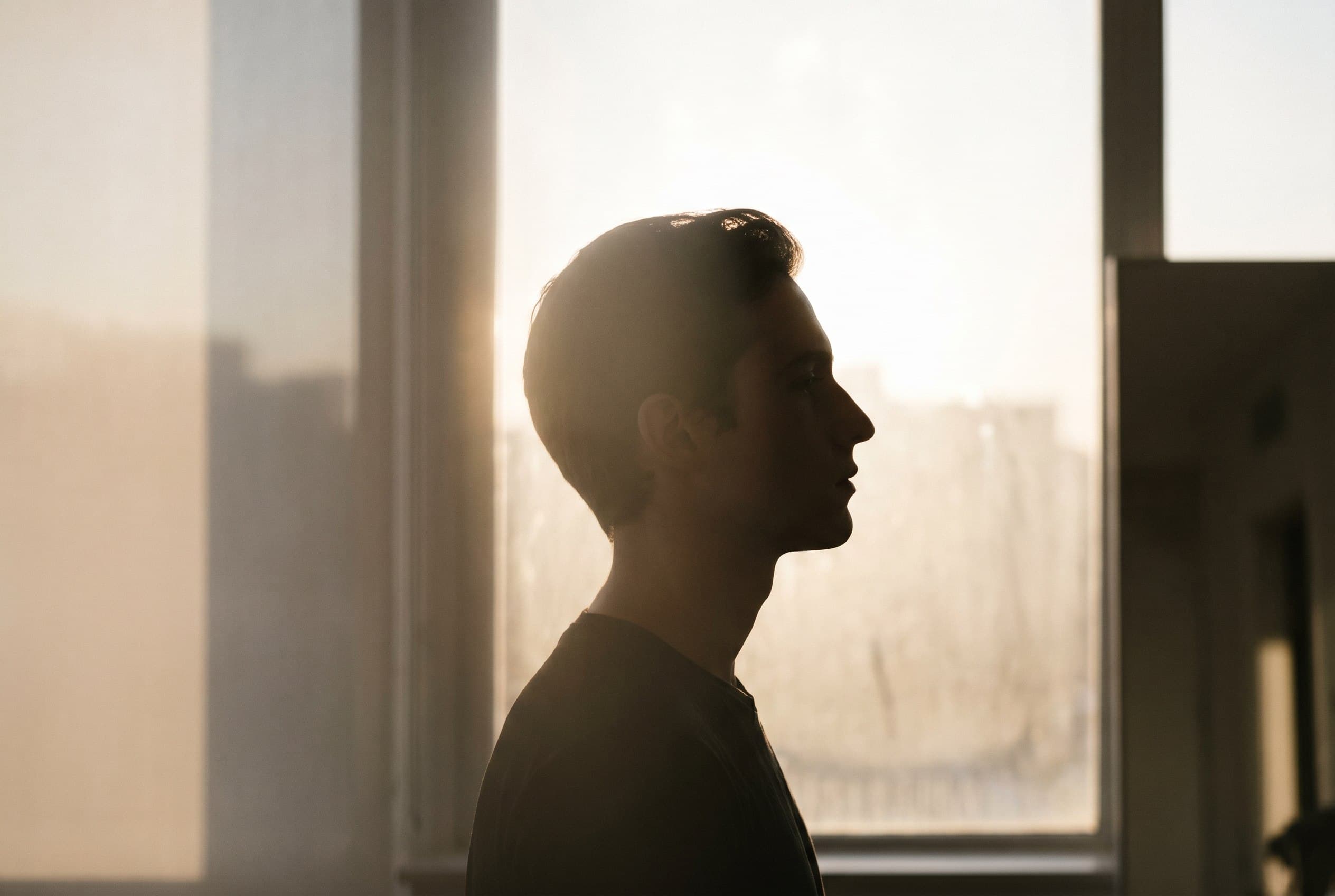 An editorial silhouette in profile against a softly lit window